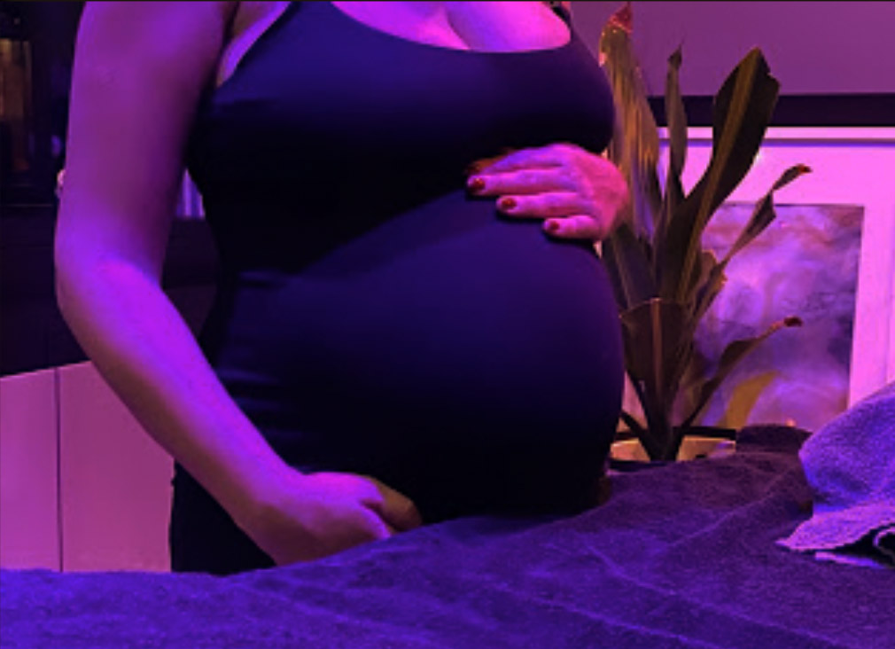 Femme enceinte debout devant une table de massage prête à se faire masser