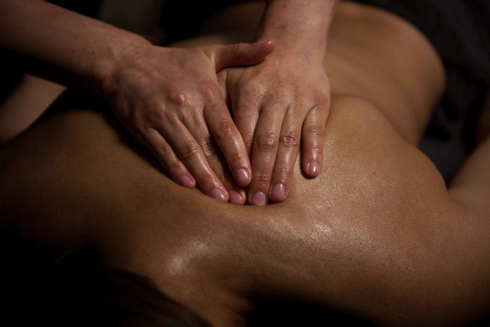 Massage du dos, omoplates et épaules avec de l'huile, personne couchée sur le ventre