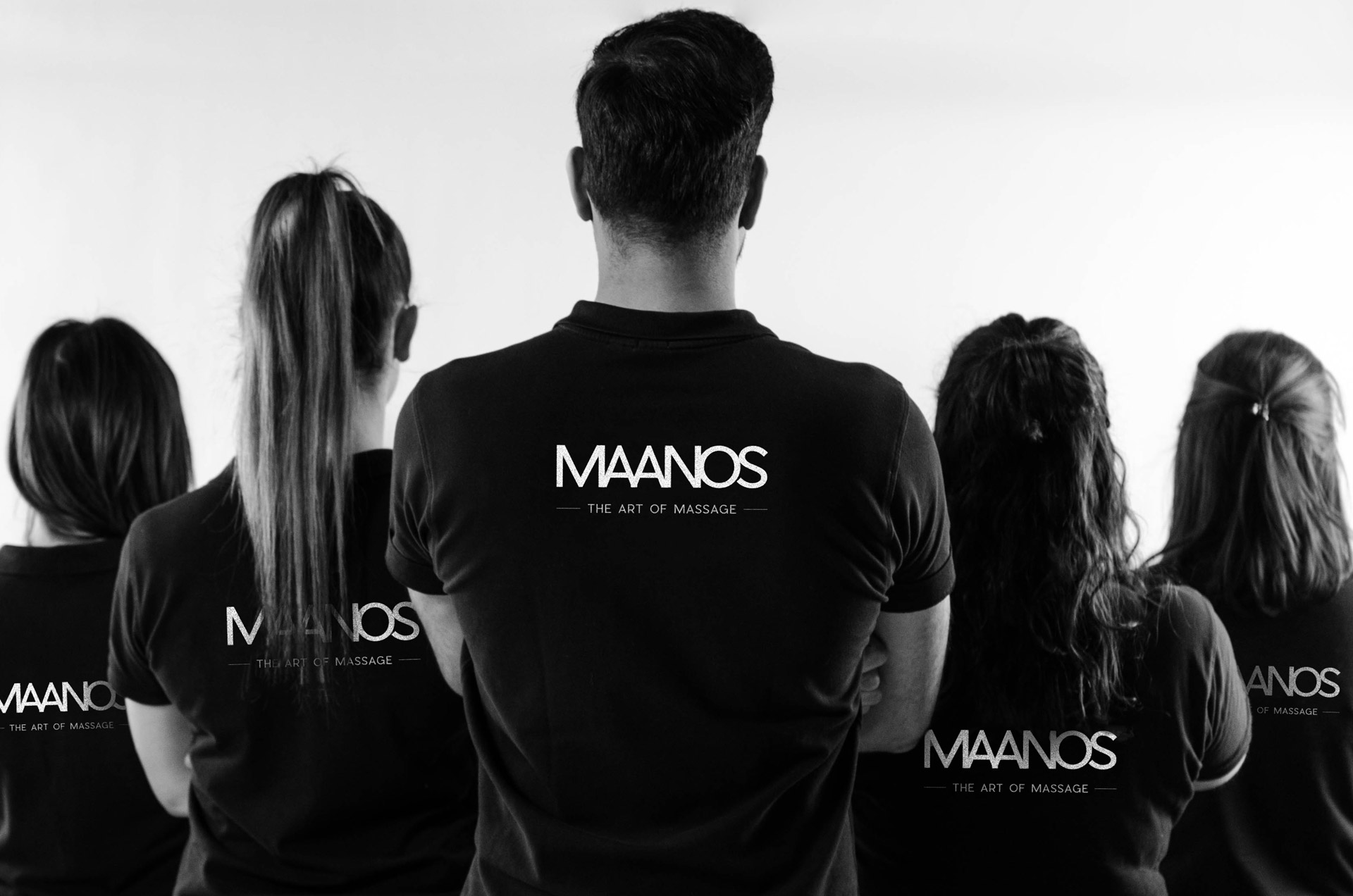 Équipe de masseurs Team Maanos de dos, bras croisés, prêts à vous satisfaire
